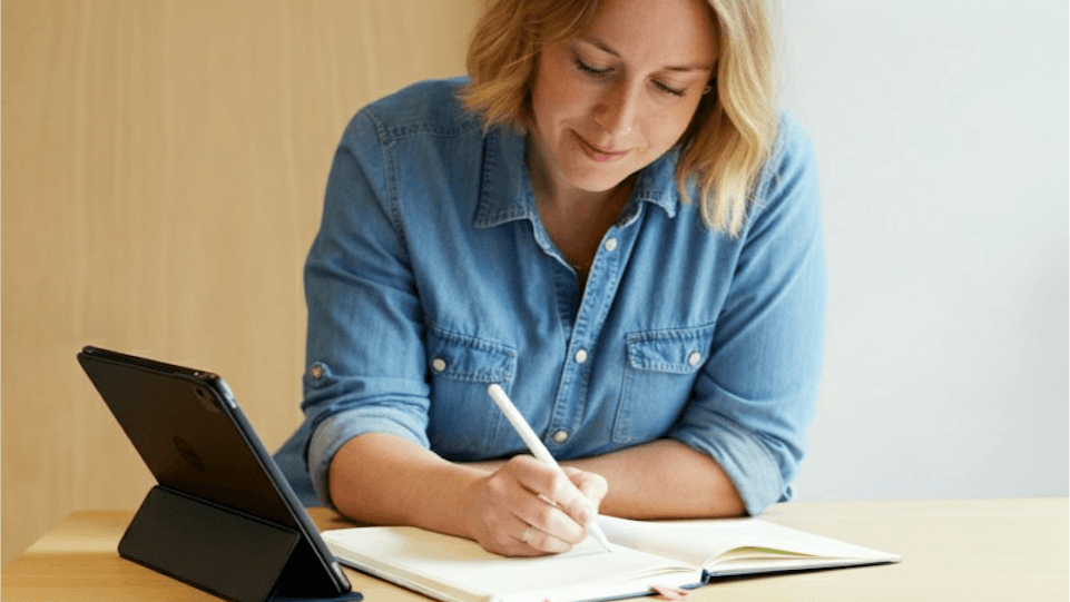 Woman in blue shirt working on her laptop by desk