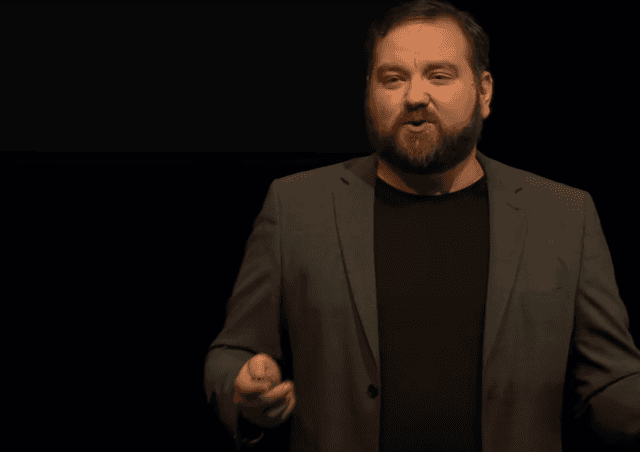 Image showing TED Talk Keynote Speaker Jerry Silfwer on stage with a black background and in a suit.