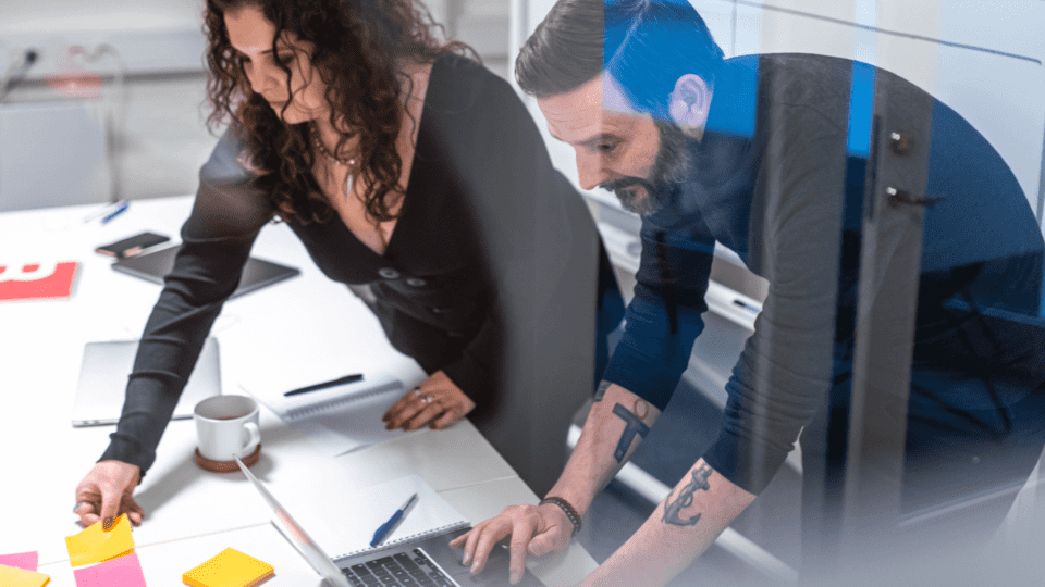 Two people in the office looking at the papers on the desk