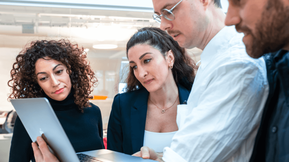 Four people in the office looking at the laptop