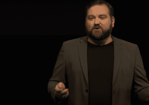 Image showing TED Talk Keynote Speaker Jerry Silfwer on stage with a black background and in a suit.