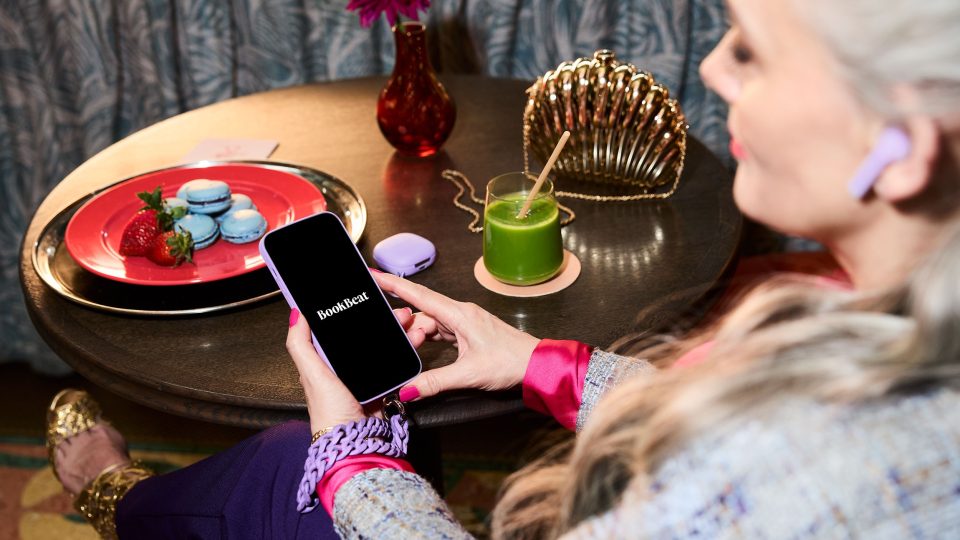 Kvinna öppnar BookBeat-appen i mobilen